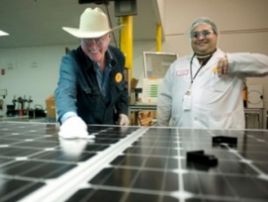 Two people examine a solar panel in a lab
