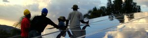 Four technicians set up a solar array at sunset