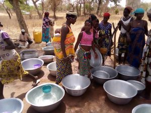 Women and children fill silver basins with clean water from a solar-powered pump