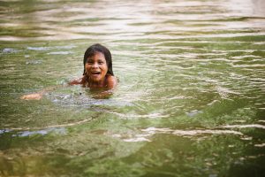 A child swims and smiles in a lake in Colombia