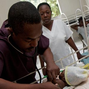 A doctor in Haiti checks the vitals of a newborn child