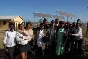 A group of people stand in front of newly installed solar panels