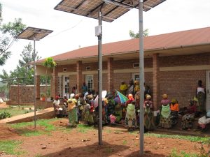 People in Rwanda gather outside a brick building powered by solar panels