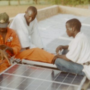 People assemble solar panels on a rooftop in Jigawa State, Nigeria to power the Whole Village Development Model