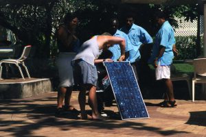 People gather around a solar panel being set up in the Solomon Islands