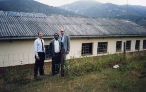 Three men stand in front of a building with newly installed solar panels