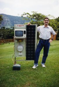 SELF's executive director stands next to a solar energy system in South Africa
