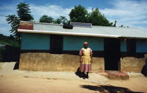 A woman stands outside her home in South Africa, which has just been equipped with a solar panel
