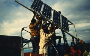 People lift up a solar panel to be installed in Tanzania