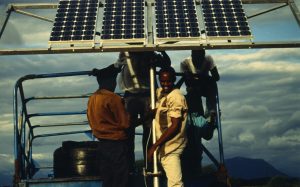 A man smiles as a solar panel is installed in a Tanzanian community
