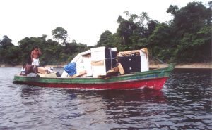 A small boat transports people and boxes down a river in the Brazilian Amazon