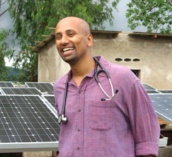 A doctor in Burundi smiles in front of solar panels