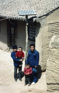 A family stands at the base of their home's new solar panel in rural China