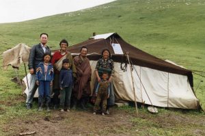 A family smiles outside a tent home in rural China after receiving a solar panel from the Solar Electric Light Fund (SELF)