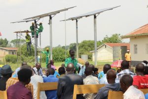 Solar energy technician speaks to a crowd of people about the new solar panels being installed in a rural village