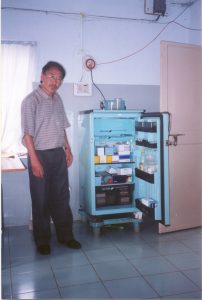 Man stands next to a medical refrigerator powered by solar energy