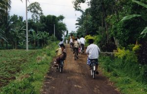 Children in Indonesia bike down a dirt road