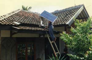 Person climbs up to a roof to set up a solar panel