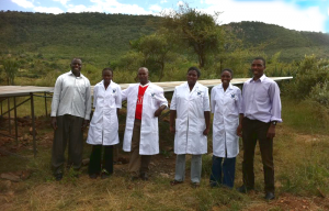 Medical staff in Kenya smile for a photo in front of new solar panels