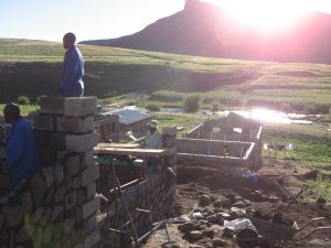 People build stone structures against a sunset in Lesotho