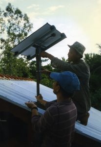 Two people install a solar panel on a rooftop