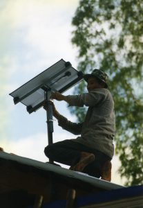 A man on a roof in Vietnam adjusts a small solar panel