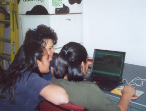 Three women look at a laptop powered by solar energy on Navajo land