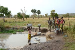 People in Benin gather water from an open pit