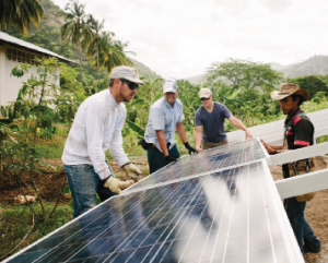 Four people install a solar array in the seaside Indigenous village of Katamsama in northern Colombia