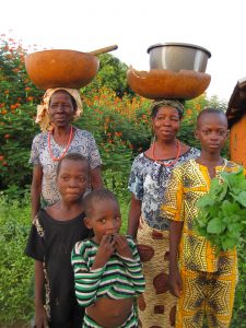 Family stand with water basins and vegetables grown in the garden