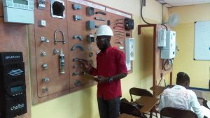 A solar technician identifies different pieces of hardware displayed on a wall in a classroom