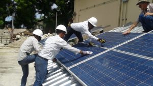 An instructor and students work on a solar panel at the National Solar Training Center in Haiti