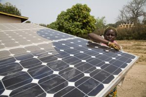 Woman in Benin washes a community solar panel