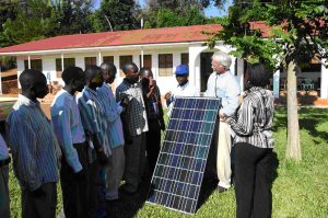 Solar engineers and locals gather around a solar panel in Tanzania