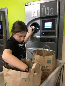 A child inserts cans and bottles into a recycling machine