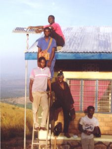 A group of people stand by a newly installed solar panel in Tanzania
