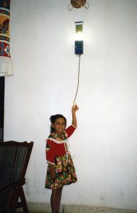 A young girl turns on a light, provided by the Solar Electric Light Co (SELCO)