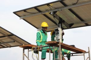 Two technicians work to install solar panels in a remote area
