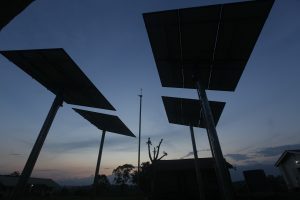 The silhouette of four solar panels against a sky at sunset