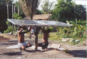 Two men wire solar panels in Brazil, surrounded by a jungle landscape