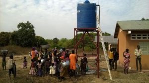 People stand at the base of a solar-powered water tank in Benin