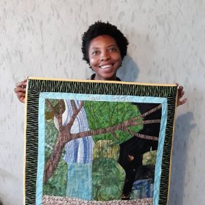 Haitian woman smiles with hand-stitched quilt