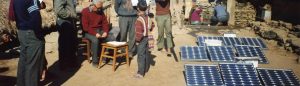 People gather by new solar panels installed by the Solar Electric Light Fund (SELF)