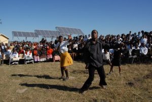 People in the Eastern Cape of South Africa dance with new solar panels behind them