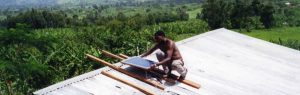 Man in Uganda configures solar panel from the Solar Electric Light Fund (SELF)