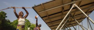 Two women in Benin clean their solar panels from the Solar Electric Light Fund (SELF)