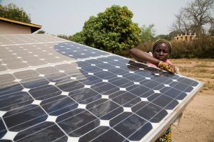 Woman cleans off a solar panel that provides energy to her rural community