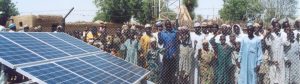 Group of people in Jigawa State, Nigeria stand behind a fence with a solar panel