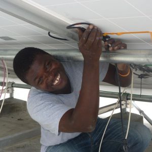 A man in Haiti wires a solar panel