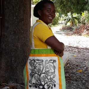 Haitian woman poses with a bag made through Peace Quilts program